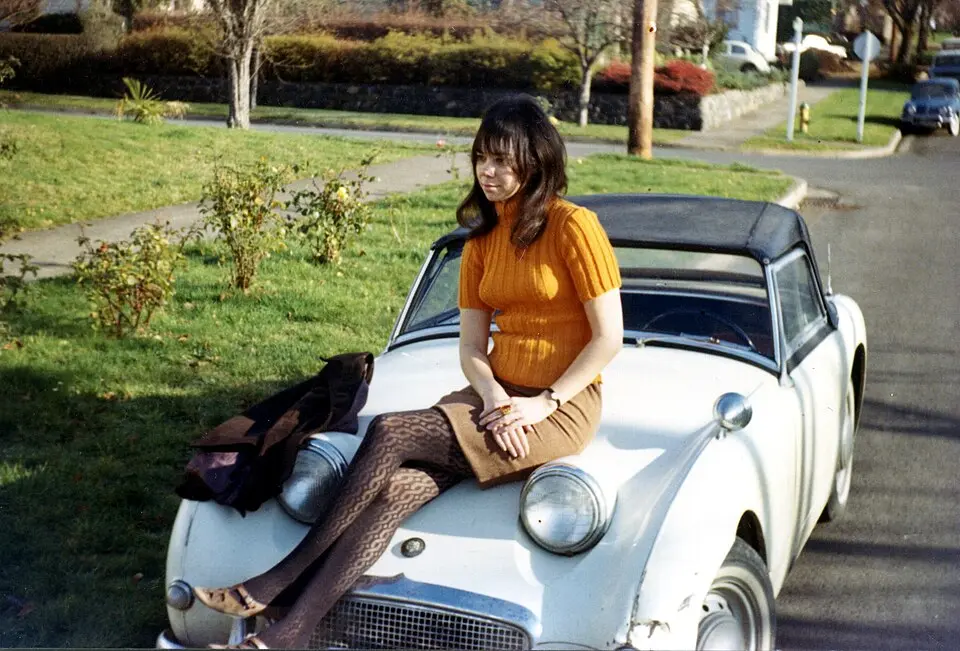 1966〜67年、オレゴン州でオレンジ色のセーターとミニスカート姿で車に腰掛ける女性